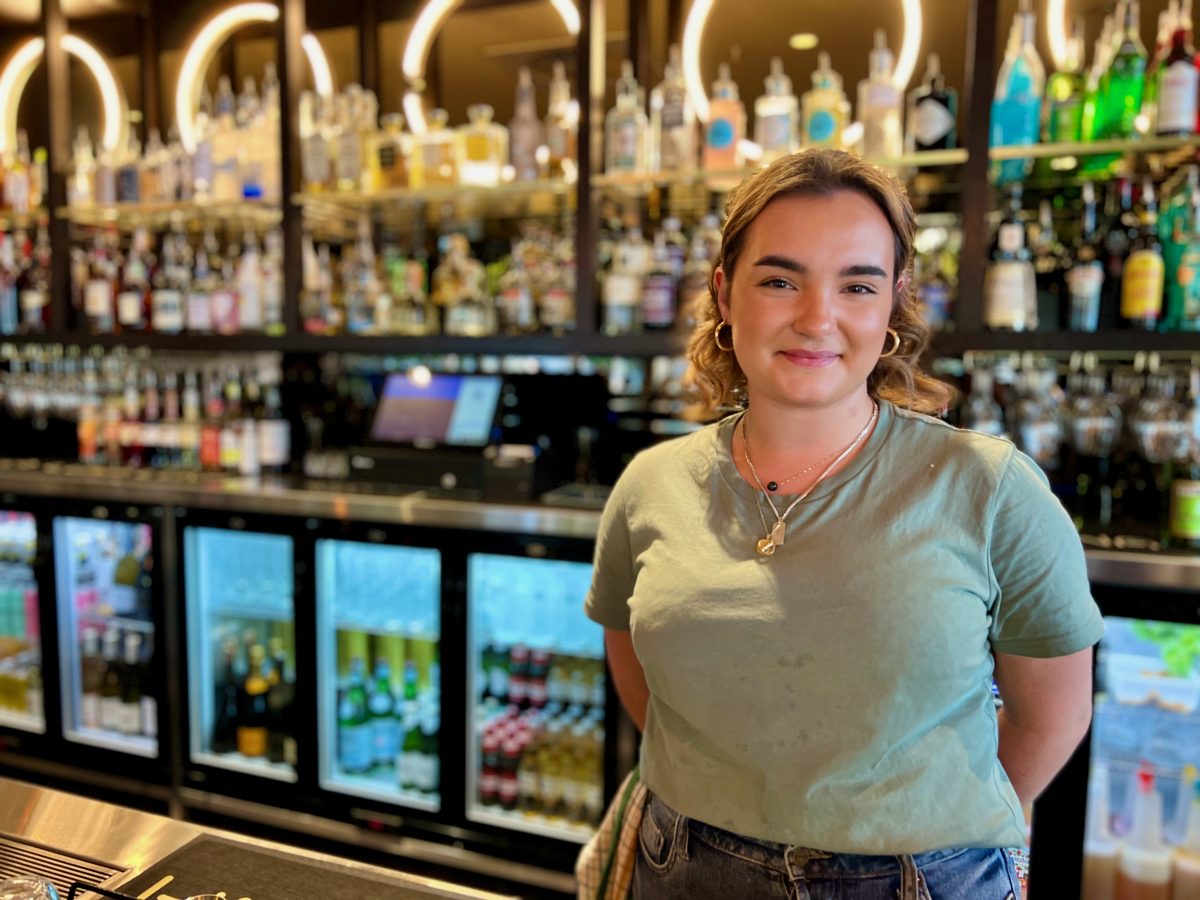 Charlotte Charli Stephenson wears olive green shirt and smiles in front of Luna Bar
