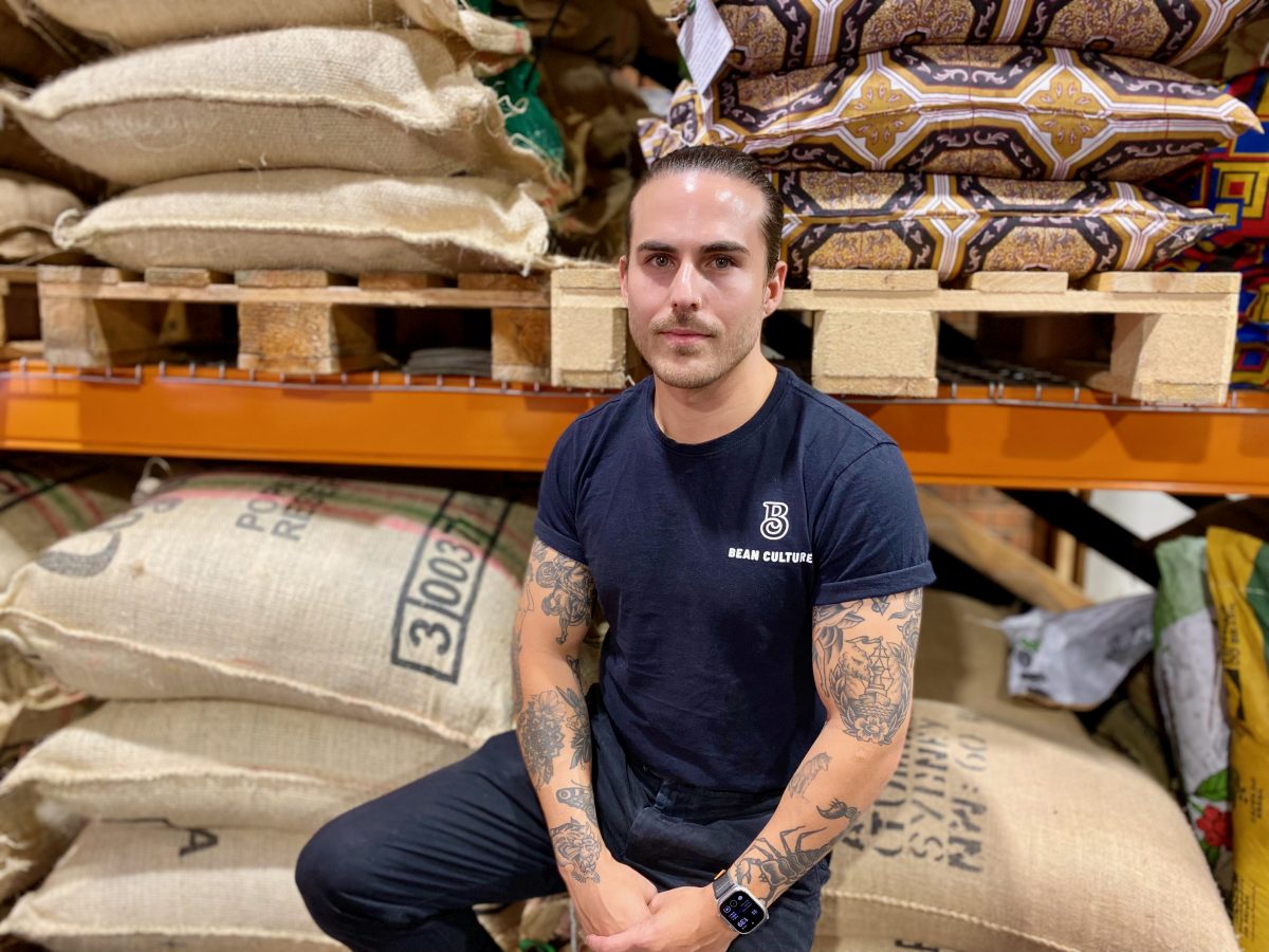 Michael Phelan sits on sacks of coffee beans at Bean Culture