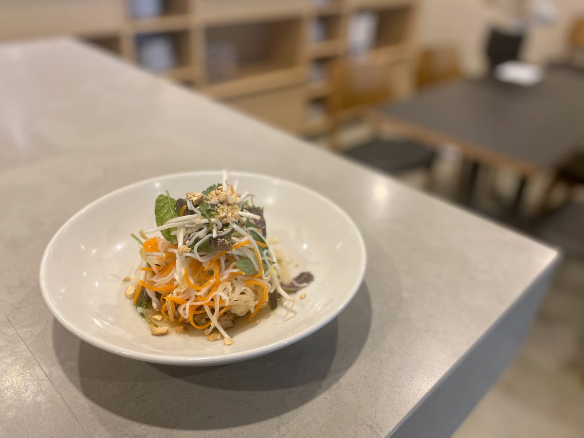 White bowl with a pile of salad and herbs.