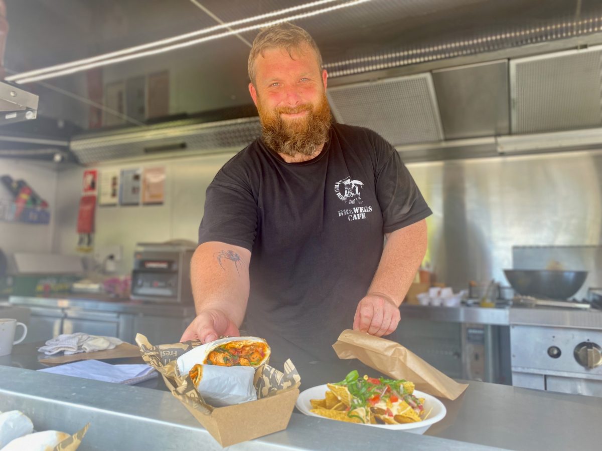 Matthew smiles and serves a chicken wrap