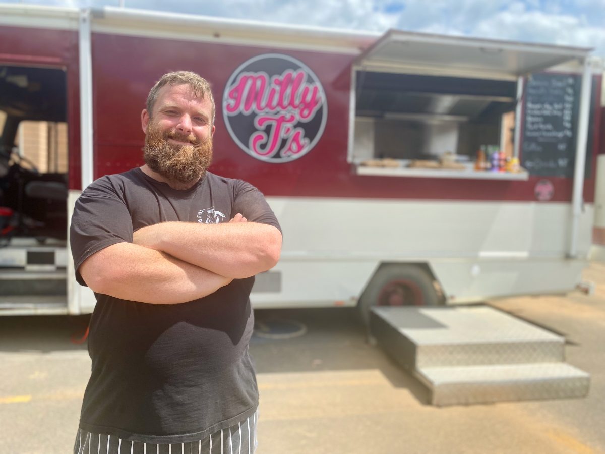 chef stands with crossed arms in front of a food truck