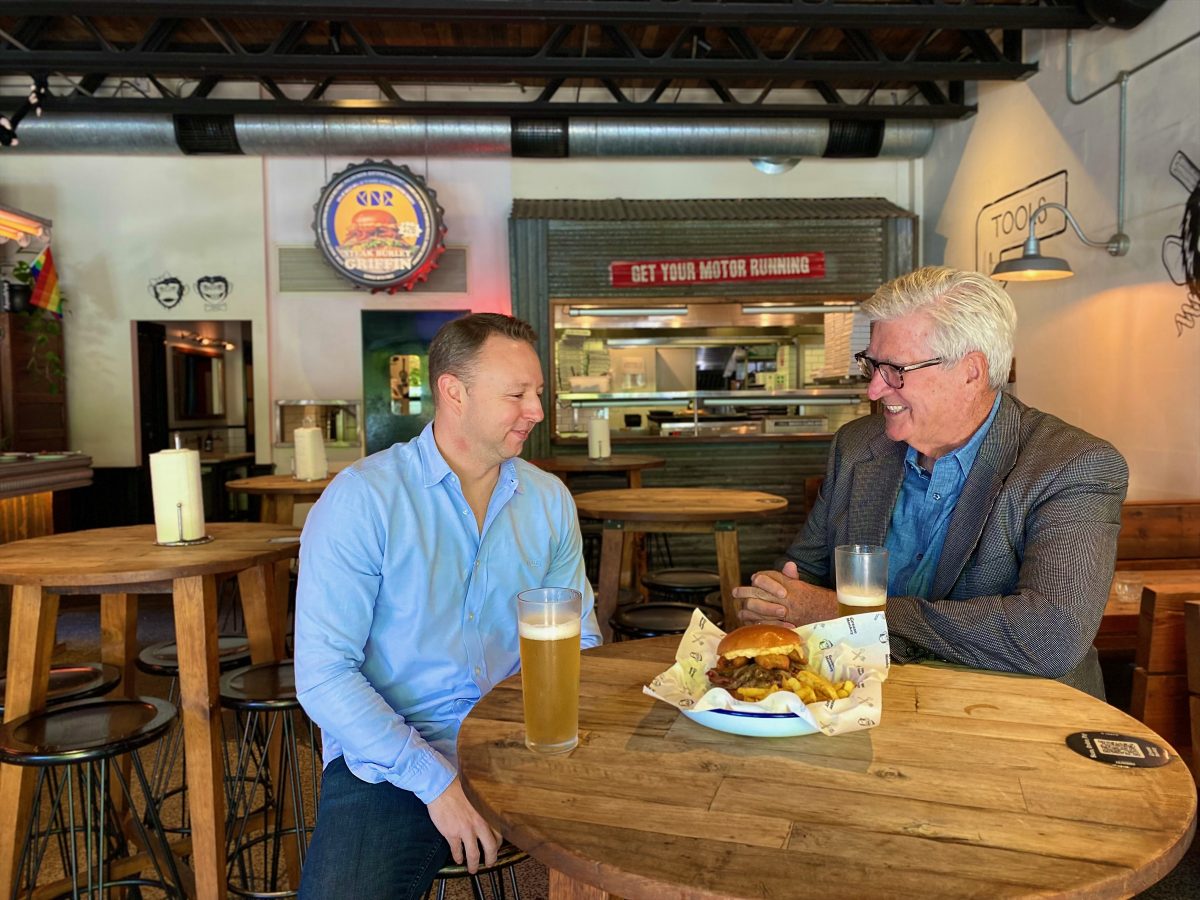 Two men with beers and burger