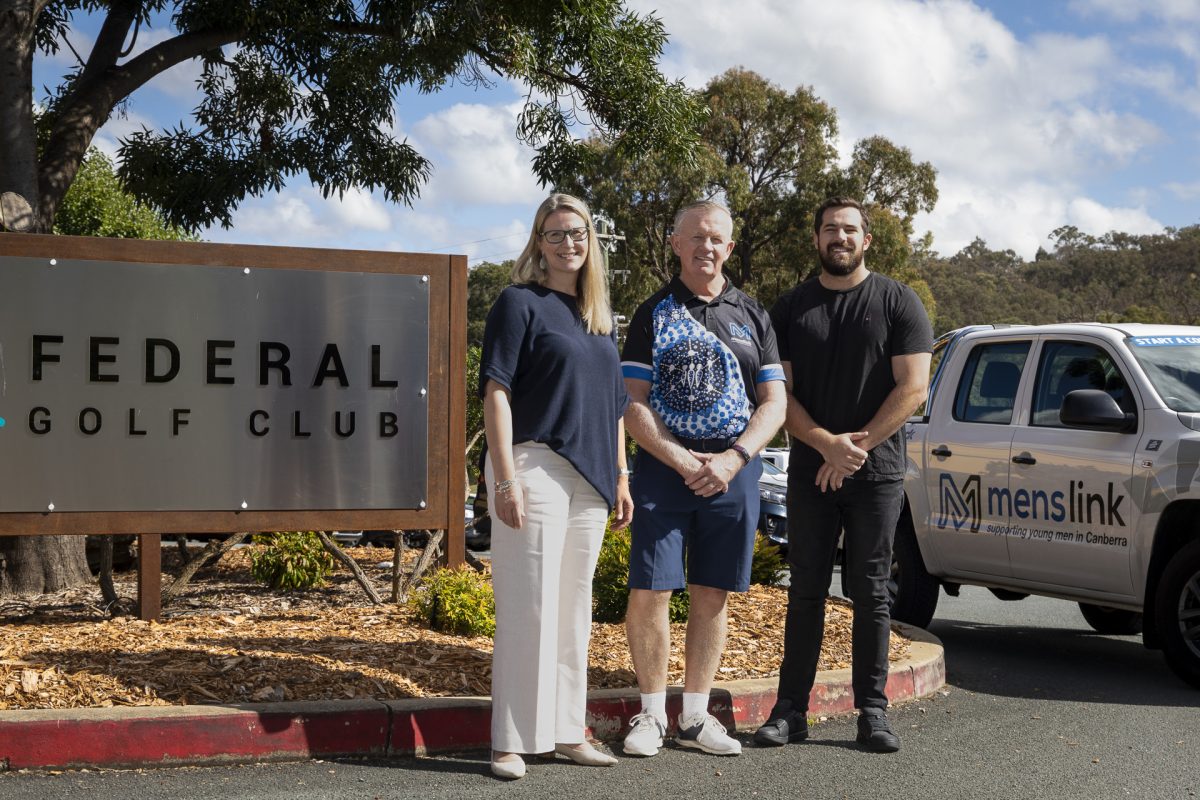 three people standing in front of signage