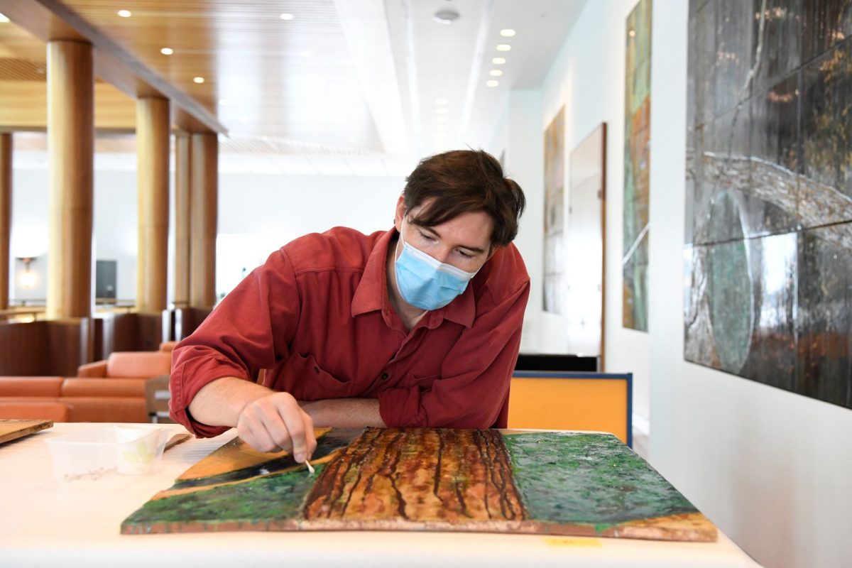 Conservator examines mural tile.