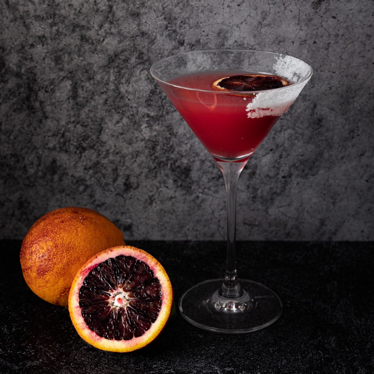 Blood Orange cocktail in martini glass with cut orange beside