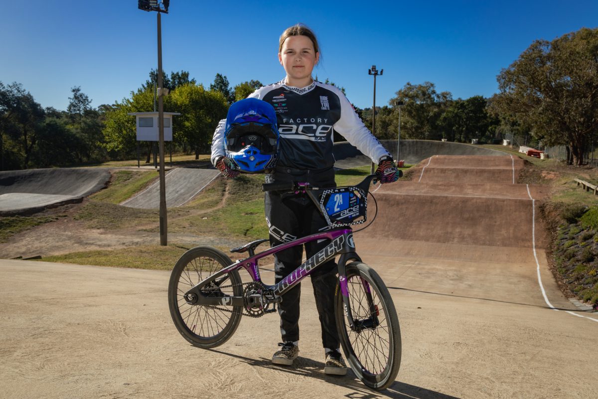 young girl holding a bmx helmet next to a bike