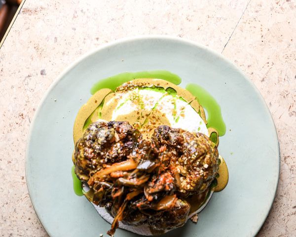 Vegan satay cauliflower features macadamia emulsion, cauliflower leaf kimchi and peanut brittle. 