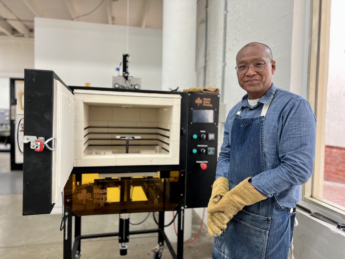  Jeffrey Sarmiento stands next to the ANU 3D glass printer