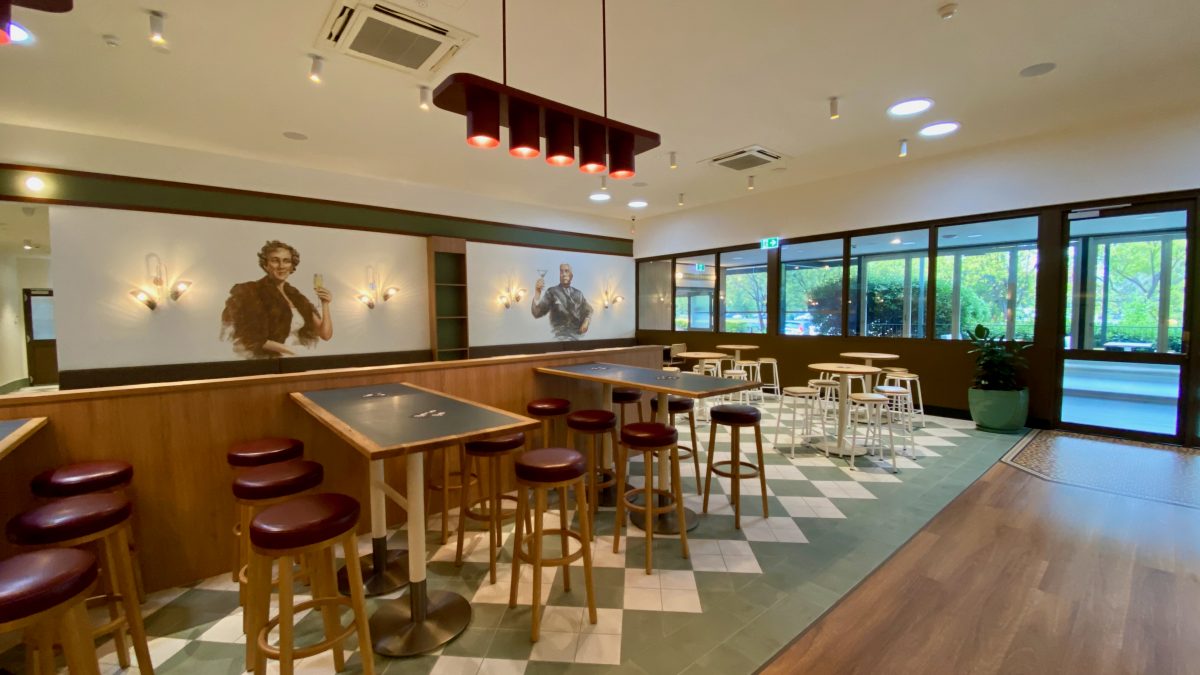 1970s style bar interior with political cartoon style mural of a woman and a man toasting champagne flutes