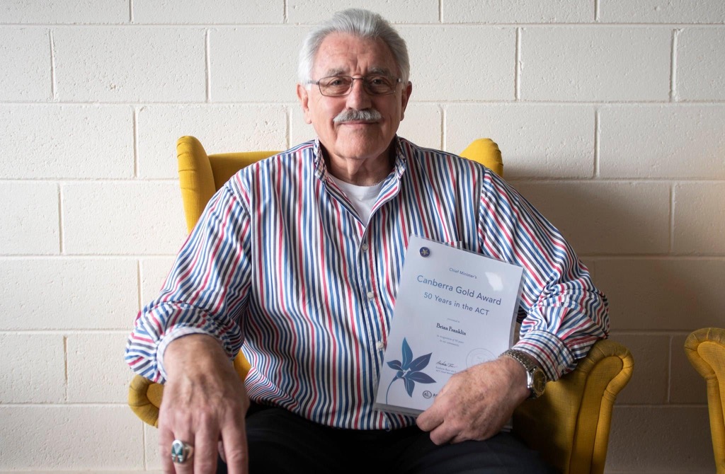 Brian Franklin sitting with an award