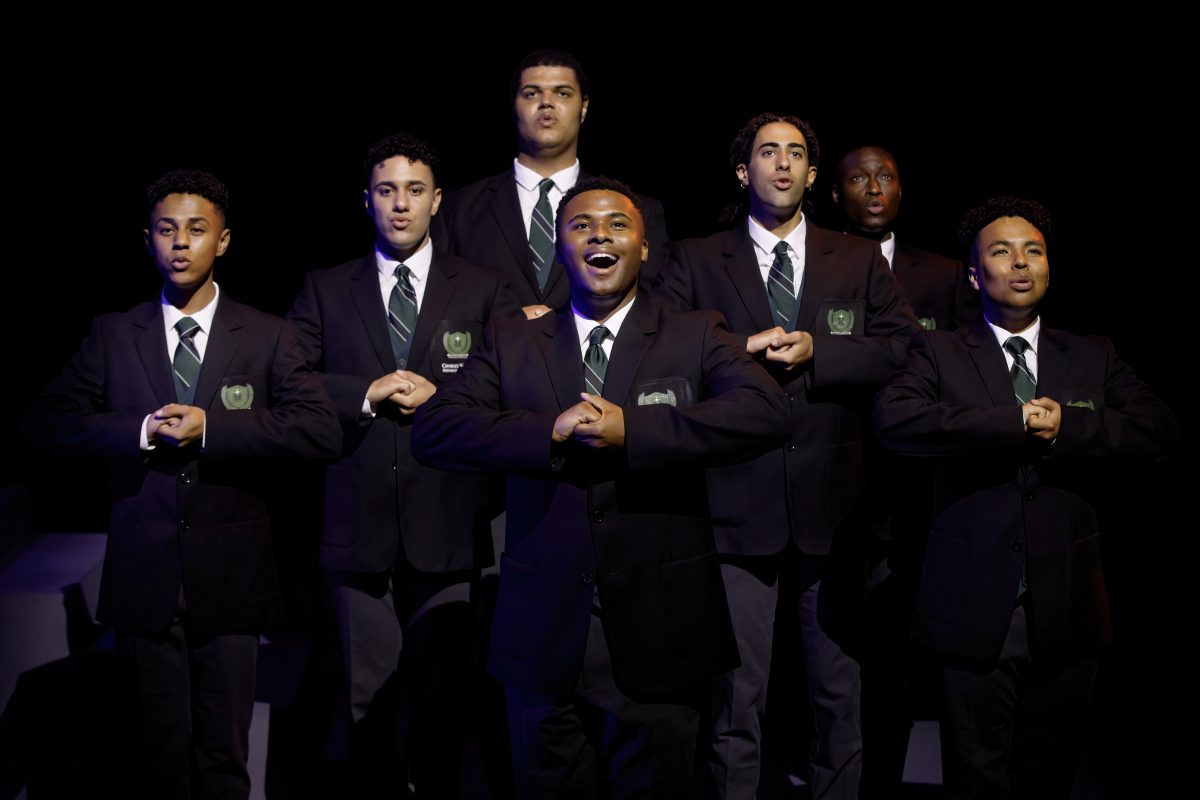 group of people singing in suits on stage