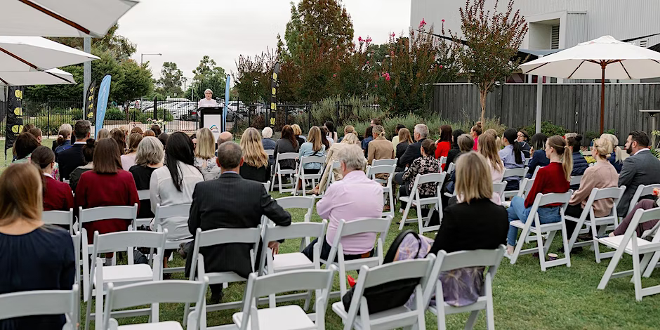 People sitting in rows of chairs facing an outdoors Tennis ACT lecturn