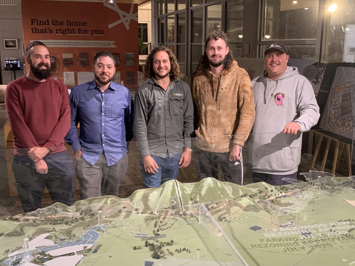 Four local recreational fisherman and Tyson Powell in the middle standing in front of a model of Ginninderry inside 'The Link'.