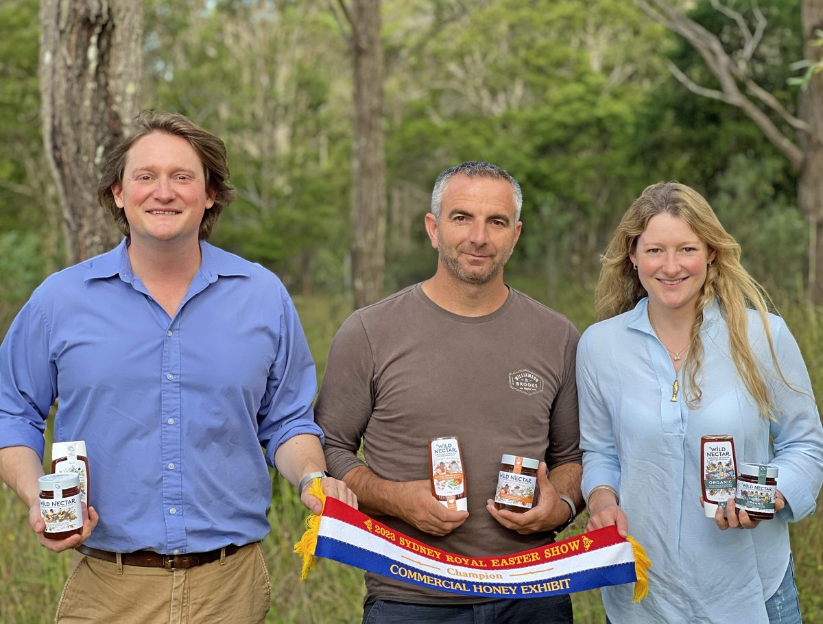 three people pose with jars of honey and award ribbon