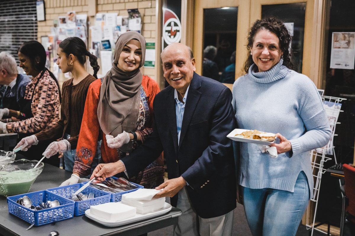 HelpingACT founding president and 2022 Canberra citizen of the year Mohammed Ali helps to serve dinner