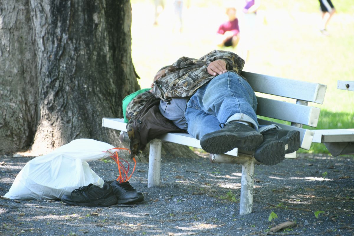 Homeless man sleeps on a park bench