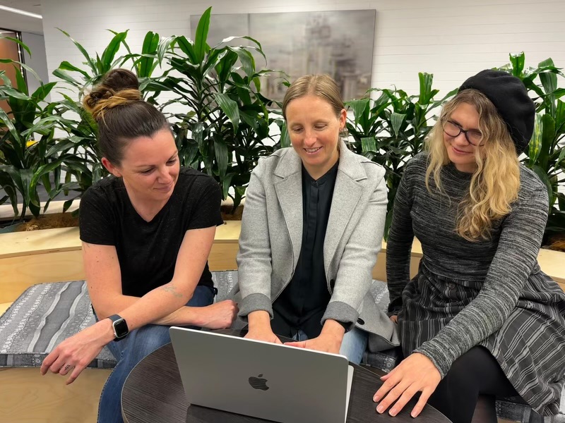 three women looking at a computer