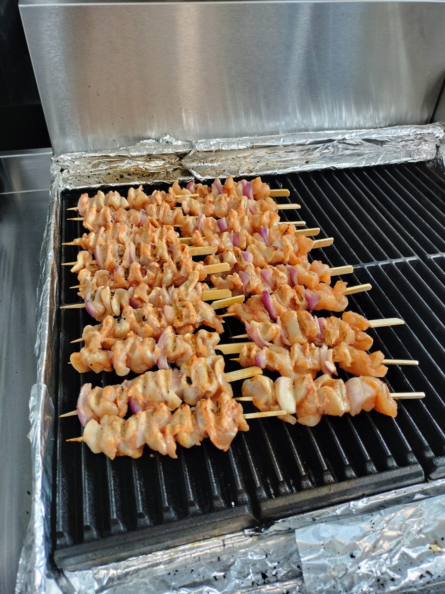 A row of uncooked Dak-kkochi skewers on a grill