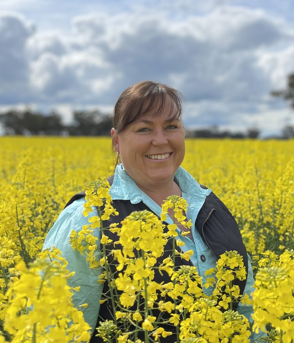 woman in a blue shirt and black vest standing in a field