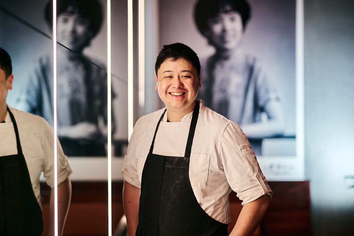 Chef Gerald smiles in front of black and white photo of woman