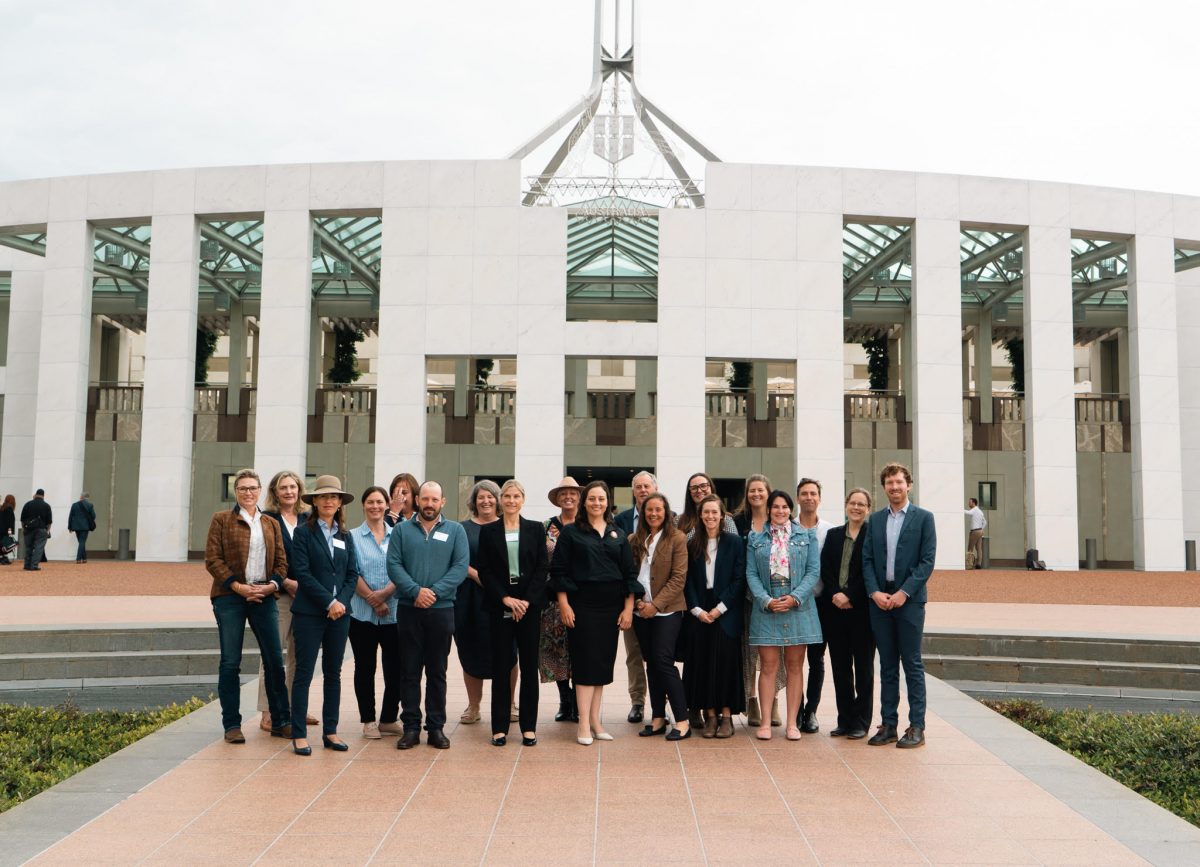 A group of people in formal attire in front of the Australian Parliament House