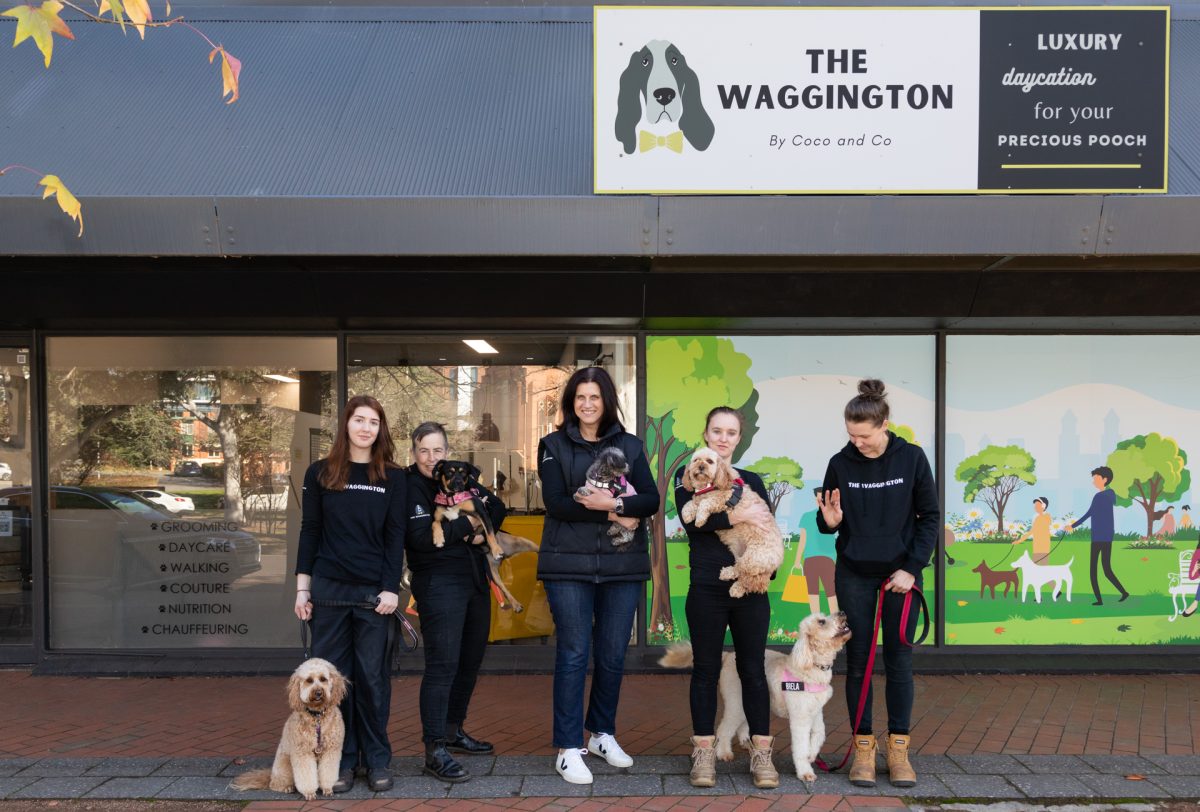 a group of people standing in front of a store with dogs