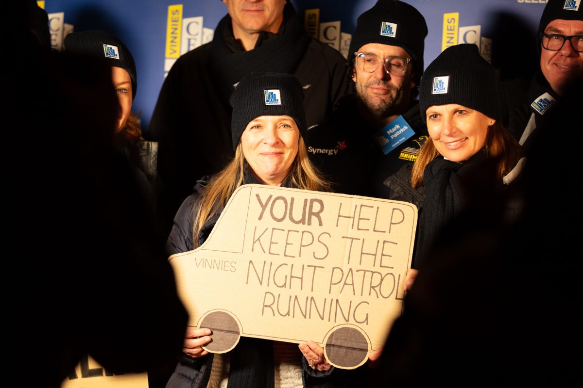 People gather together holding a sign