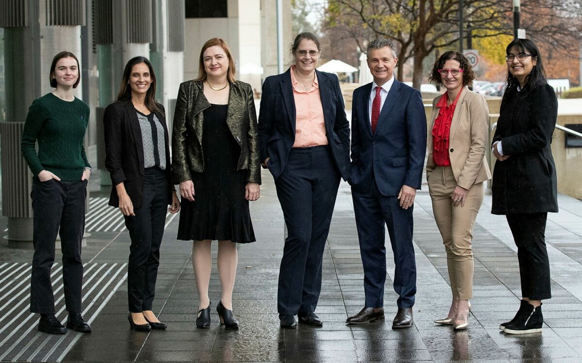 man and six women standing outside building