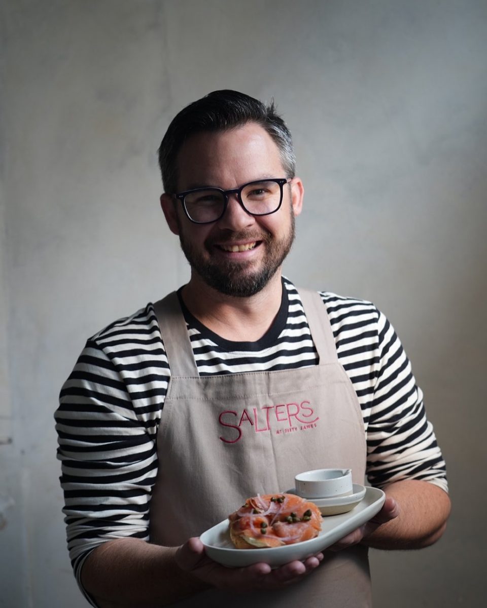 Man wearing apron smiles with coffee