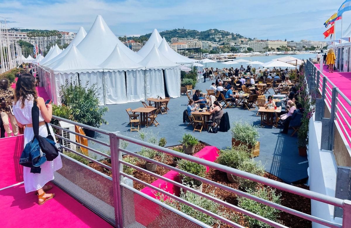 A white marquee with pink carpets and people dining outside in France