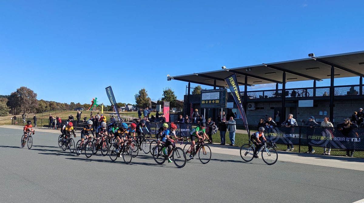 Cyclists cheered on by attendants at the fence.