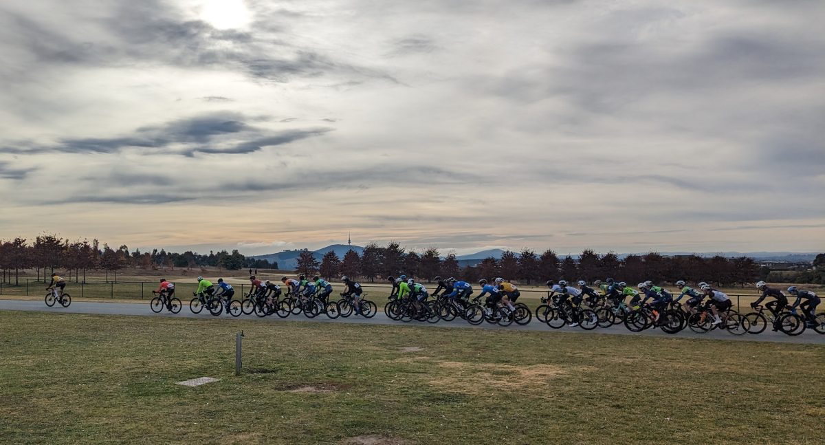 Cyclists riding on a track in a group with the Canberra landscape in the background.