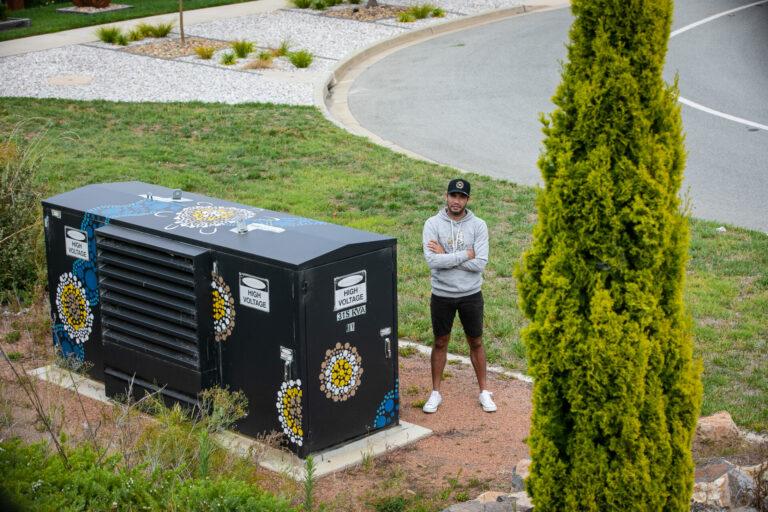 man standing next to mural on electrical substation