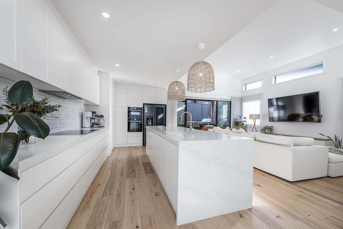 Open plan living and kitchen with wooden floors and white interiors