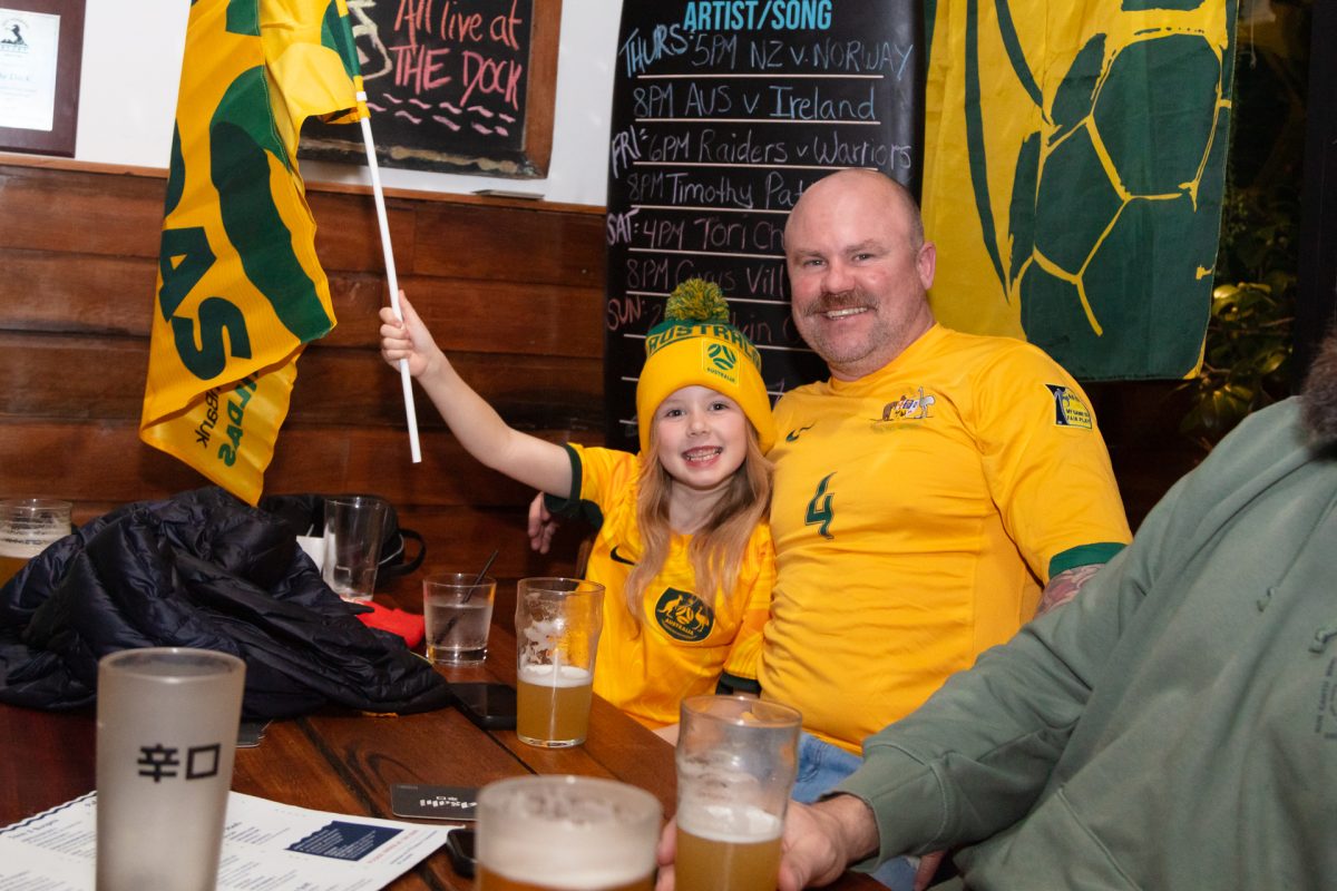 Man and child posing for a photo in Matildas attire.