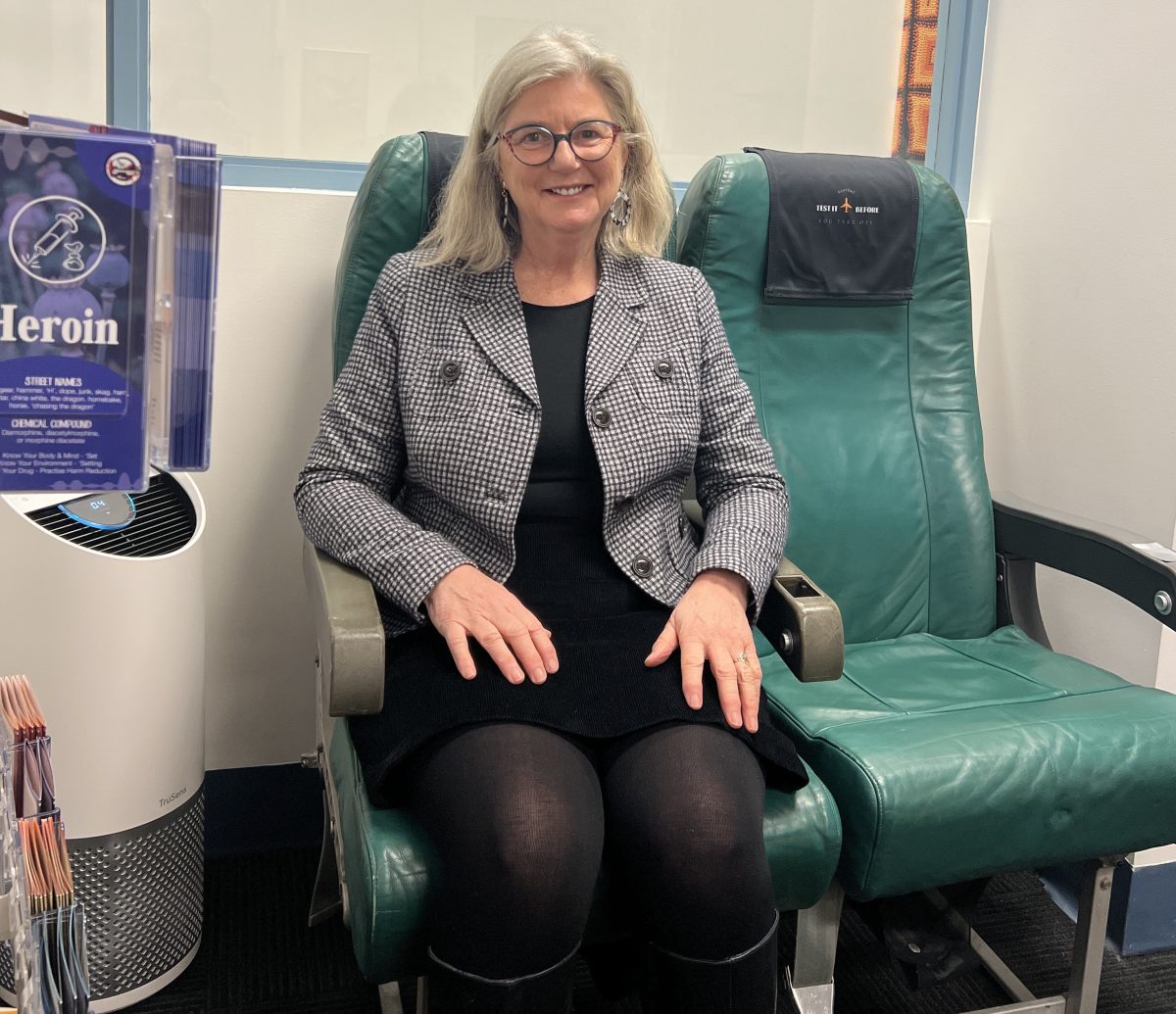 Bronwyn sitting in an airline seat that's in the reception area of CanTest.