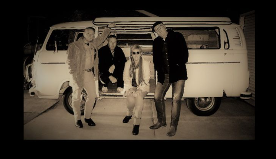 four people standing near a car