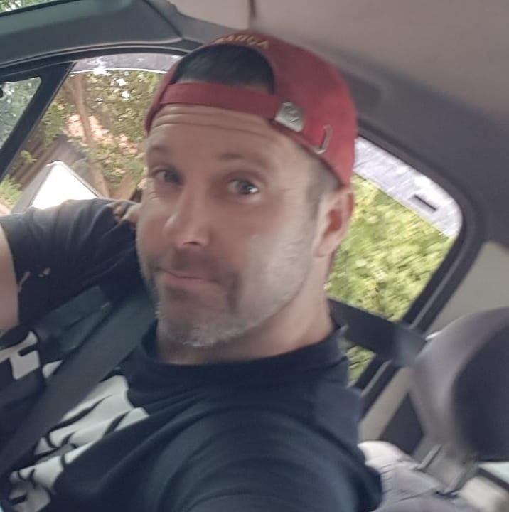 man in car wearing a baseball cap