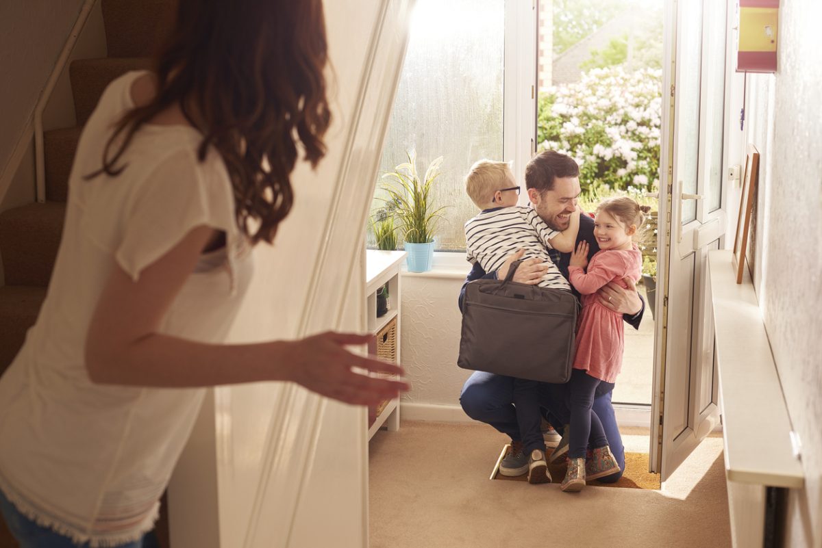 Man being welcomed home by children after work.