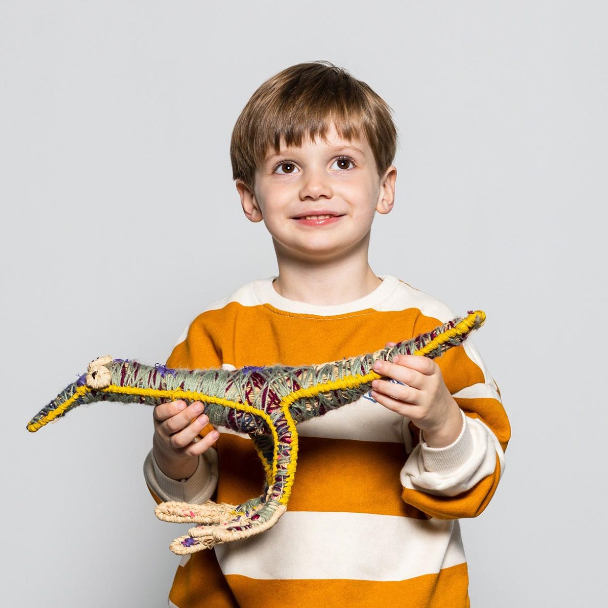 a child holding a woven dinosaur