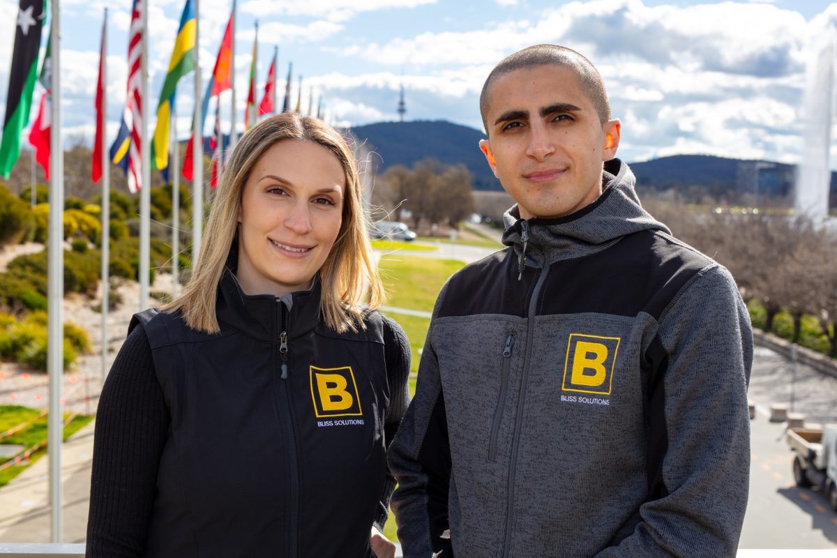 two people wearing uniform standing in front of flags