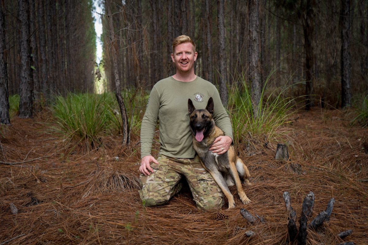 man in camo in the bush with a dog