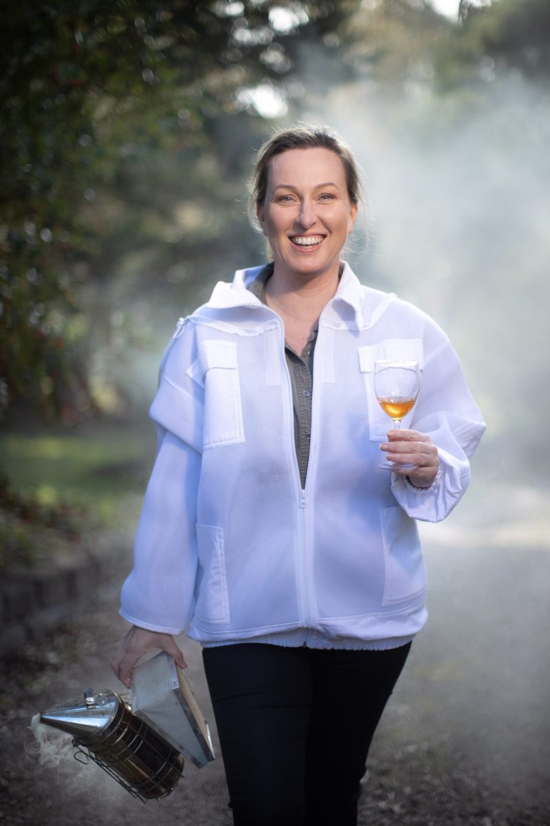 Woman with wine glass and bee smoker