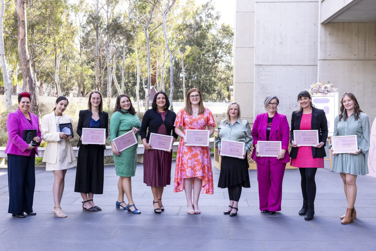 Spirit of Women Awards finalists stand in a line and hold up their plaques