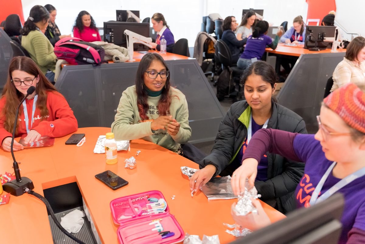 Four women from Curious Minds interact at a table