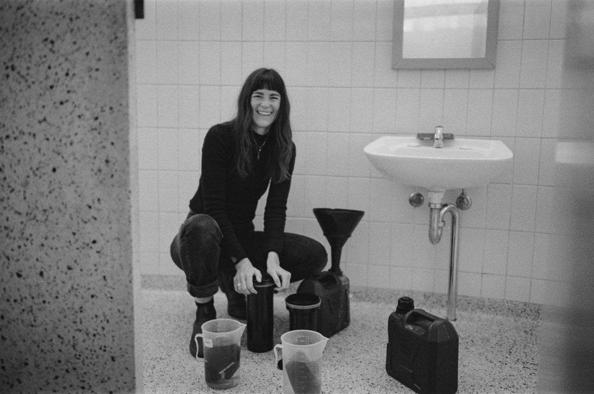 artist Sammy Hawker with jugs and containers in a bathroom