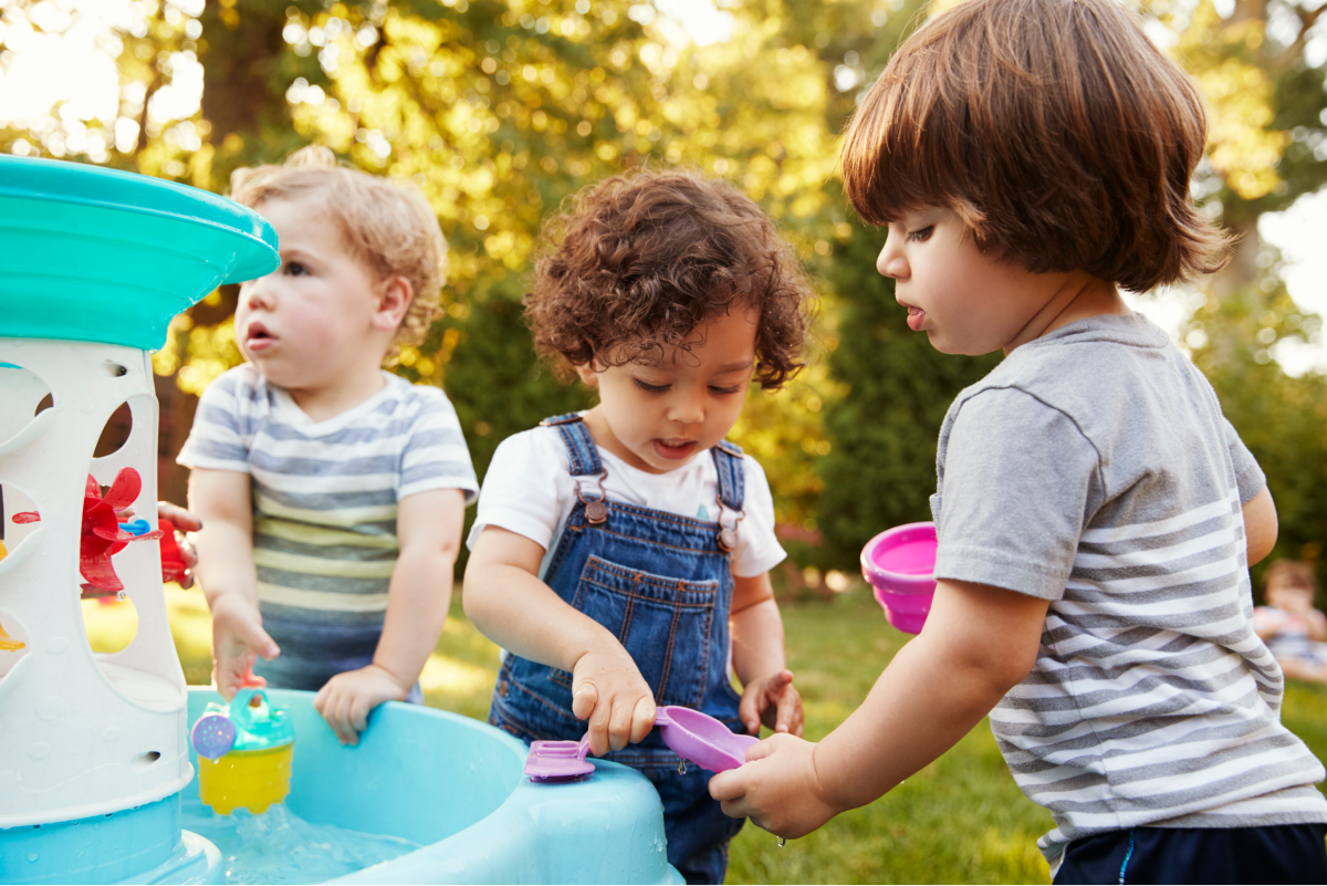 group of young children playing with a water table