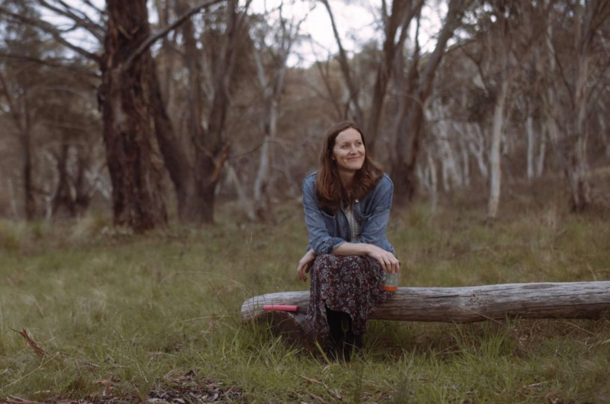 smiling Jessica Beange sits on a log 