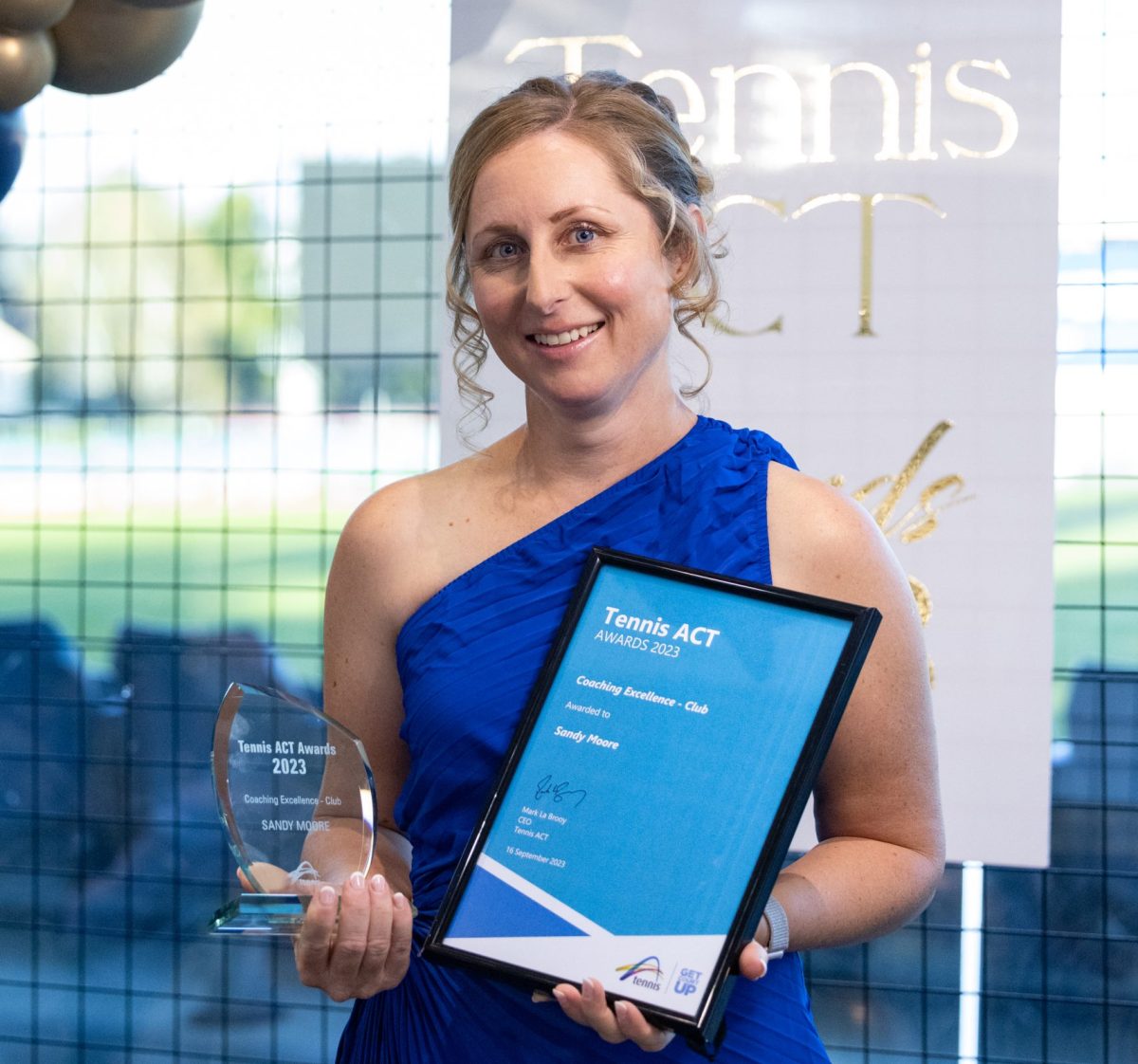 woman in blue dress holding an award