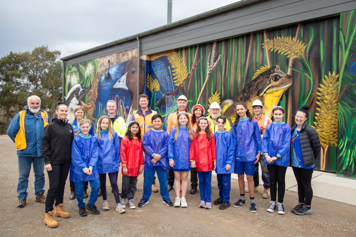 Nineteen people standing in front of artwork painted on the Evatt Odour Control Unit